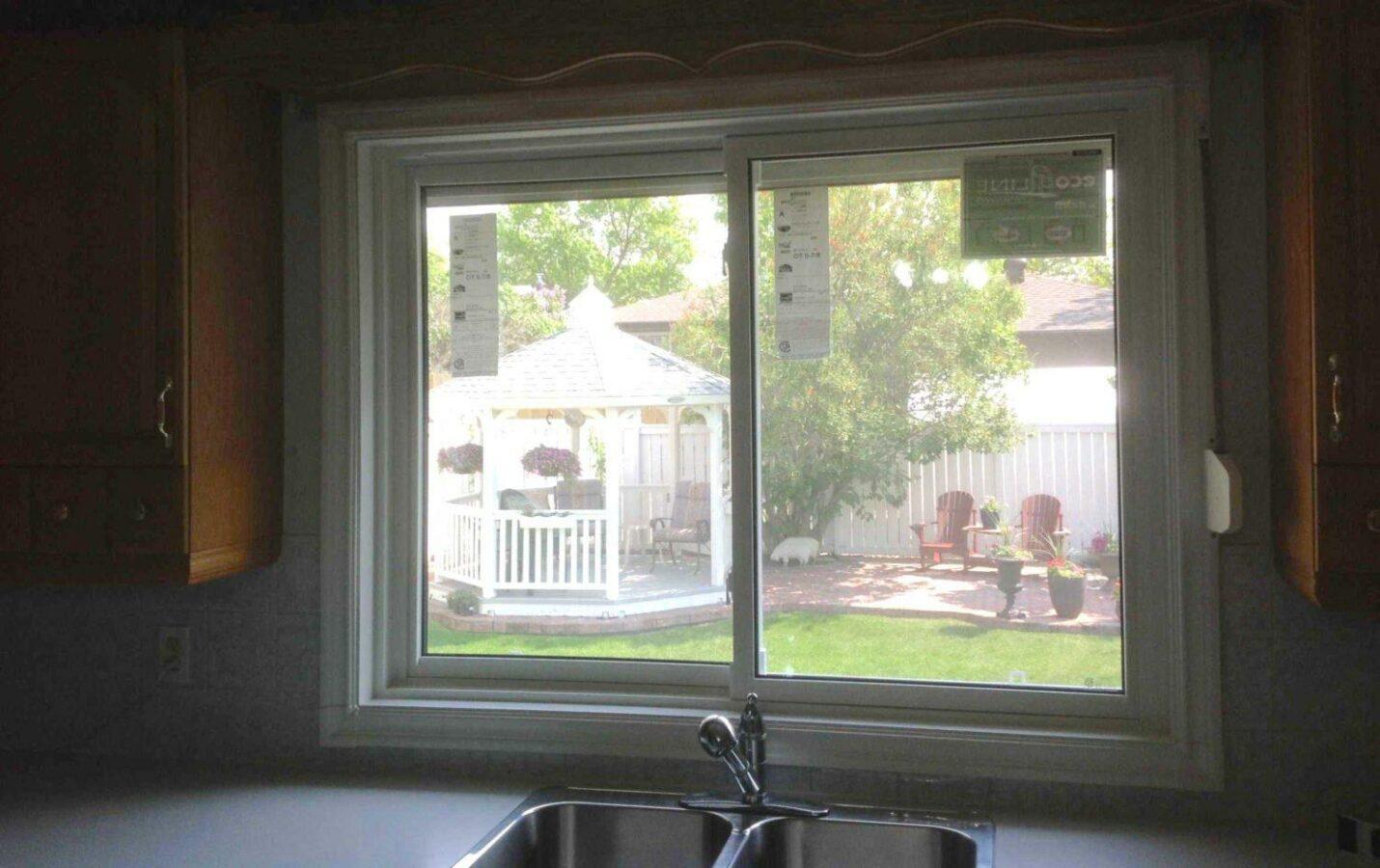 A kitchen slider window blocked by a high faucet